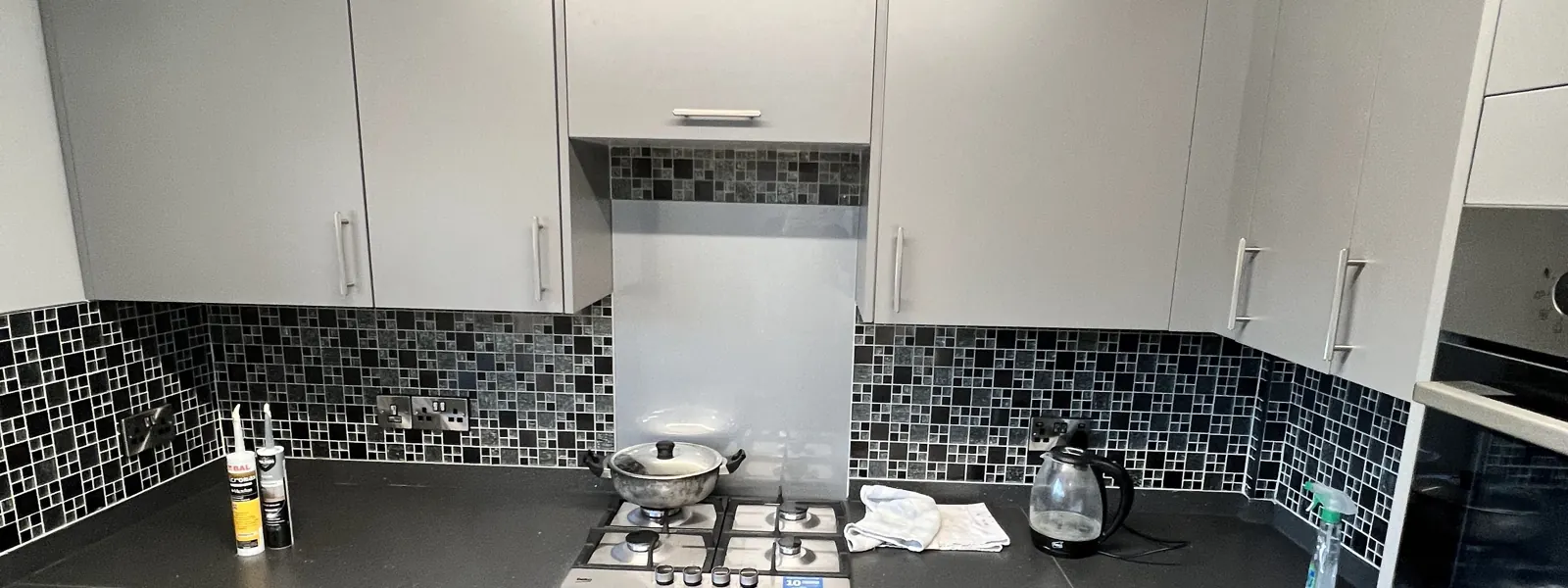 Fitted kitchen with grey cabinets and patterned splashback